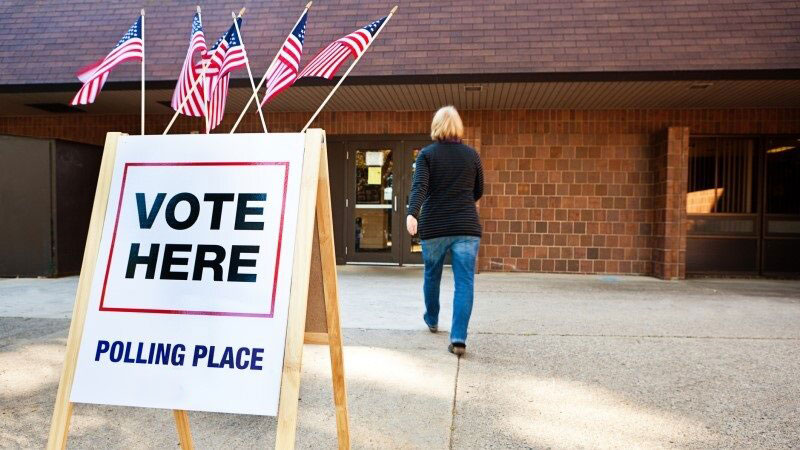 Outside a polling place with a Vote Here sign.